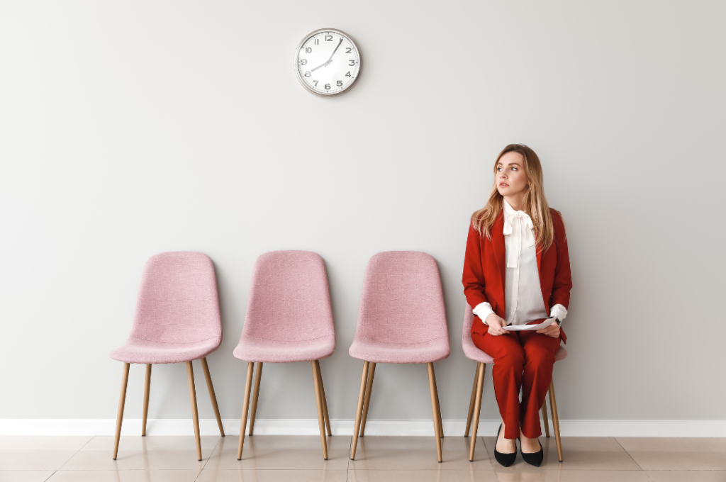 girl sitting on chair next to three empty pink chairs waiting for interview